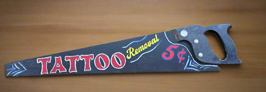 Decorative saw with ‘Tattoo Removal’ hand painted on it.