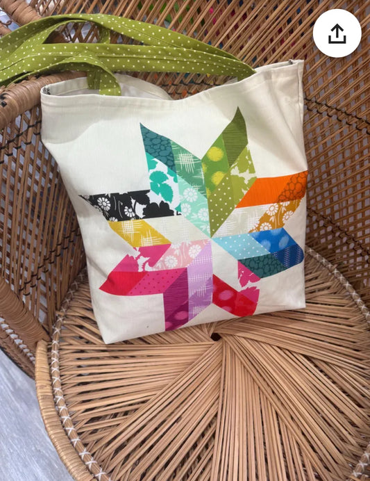 "Handmade quilted tote bag with fabric handles and decorative stitching"
