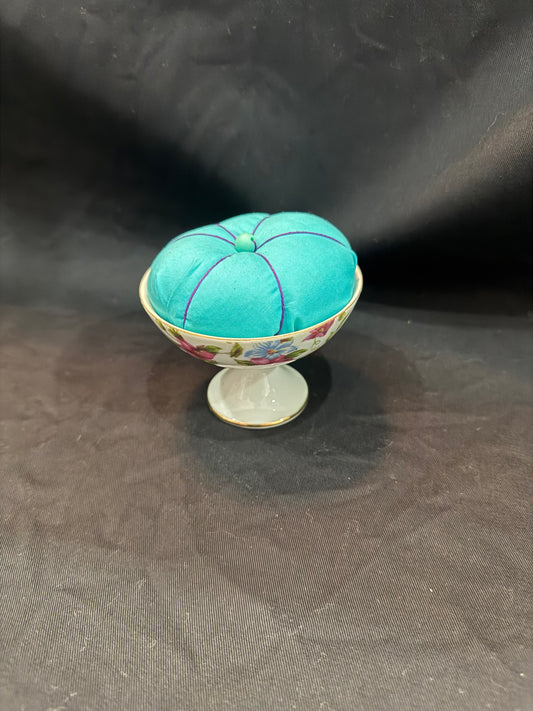"Handmade quilted pin cushion with decorative fabric and secure pin storage"
